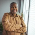 African American Senior Man at home Portrait. Smiling senior man looking at camera. Portrait of black confident man at home. Portrait of a senior man standing against a grey background